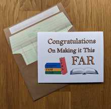 Load image into Gallery viewer, Accounting greeting card, with an image of a book titled &quot;IFRS&quot; leaning against images of 3 stacked books titled &quot;GASB&quot;, &quot;FASB&quot;, and Securities Exchange Act of 1934&quot;, and an open book sitting to the right, with text on top that reads &quot;Congratulations on Making it This FAR&quot;, atop an envelope lined in ledger paper
