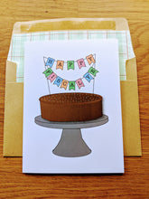 Load image into Gallery viewer, Accounting greeting card, with a chocolate frosted cake with sprinkles on a cake stand, with a banner on top reading "Happy Fiscal YE", atop an envelope lined in ledger paper