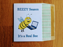 Load image into Gallery viewer, Accounting greeting card, tired-looking cartoon bee working on a laptop with text that reads "Bzzzy Season, It's a Real Bee", atop an envelope lined in ledger paper