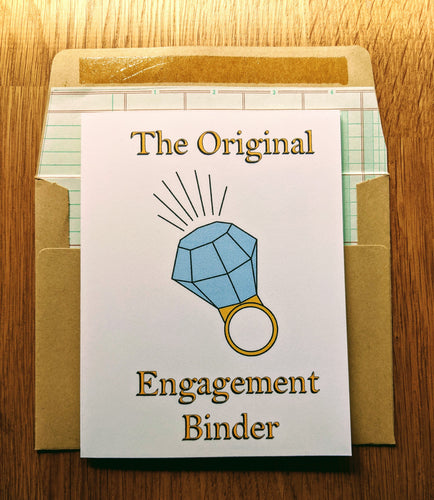 Accounting greeting card atop ledger-paper lined kraft envelope.  The card has an oversized diamond ring in the middle, with writing that states 