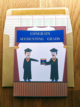 Load image into Gallery viewer, Accounting greeting card, with images of a graduation stage with a graduate in cap and gown walking towards a professor in cap and gown, being handed a stack of four CPA Exam review books, with text on a banner that reads &quot;Congrats Accounting Grads&quot;, atop an envelope lined in ledger paper 
