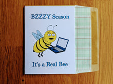 Load image into Gallery viewer, Accounting greeting card, tired-looking cartoon bee working on a laptop with text that reads &quot;Bzzzy Season, It&#39;s a Real Bee&quot;, atop an envelope lined in ledger paper
